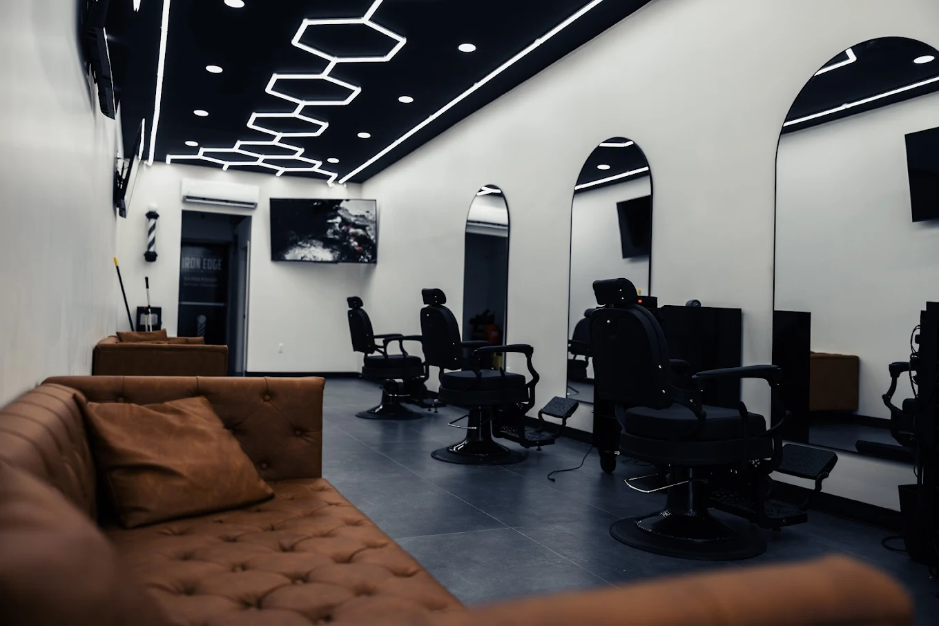 Inside Iron Edge Barber Co. — four barber chairs lined up under hexagonal LED ceiling lights